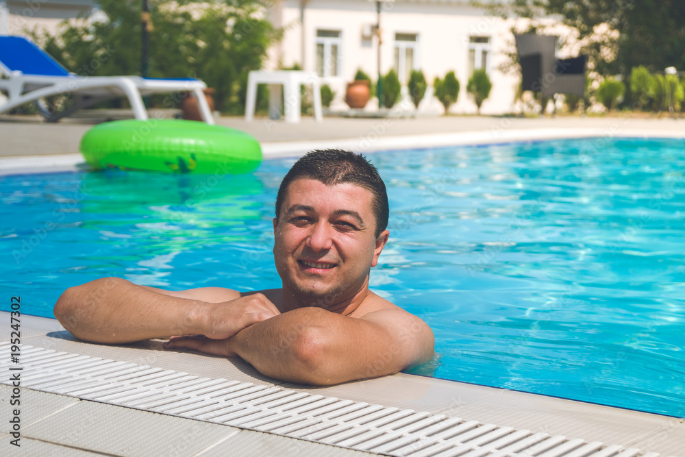 Portrait of young man relaxing in swimming pool, summer outdoor concept