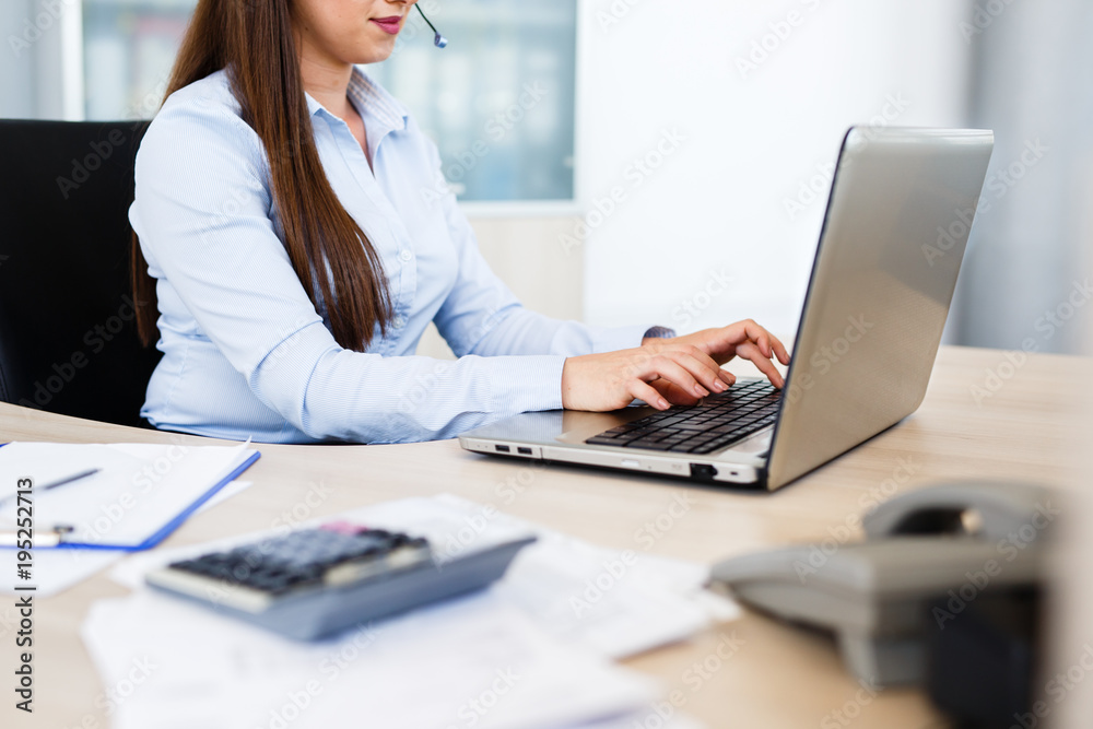 Beautiful young woman working on laptop with headphones Beautiful young woman working on laptop with headphones