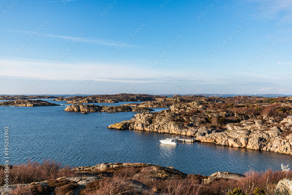 Rocky coast with small white boat and blue sky on Swedish Island, Archipelago 