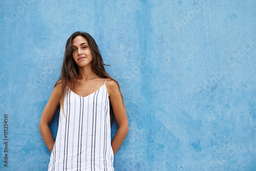 Beautiful girl in striped linen dress over blue wall. photo