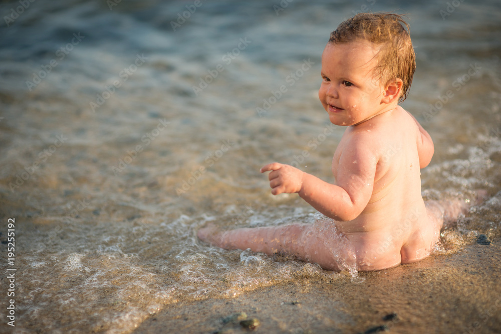 Cute baby playing in shallow sea water, holiday background Cute baby playing in shallow sea water, holiday background
