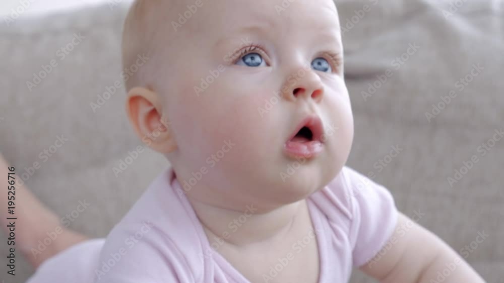 Pretty small baby with blue eyes looking attentively and smiling Pretty small baby with blue eyes looking attentively and smiling