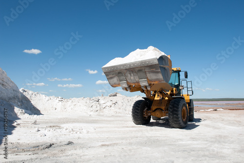 Caterpillar on wheel moves raw salt against blue sky in a salt mine in  Argentina. photo