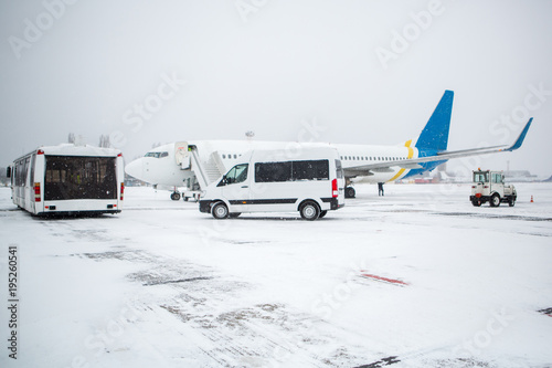 Passenger plane at airport in winter in blizzard. Landing passengers in airliner in winter during snowstorm. Modern twin-engine passenger airplane at airport during snow blizzard