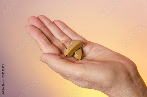 Closeup senior woman hand holding hearing aids 