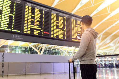 Passenger looking at flights information board in airport terminal	