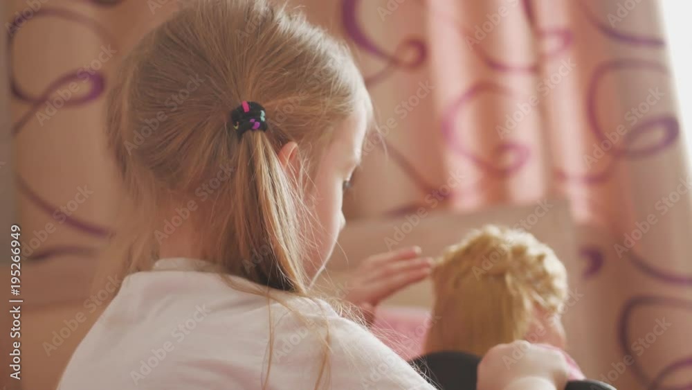 Girl combs doll hair by hairbrush