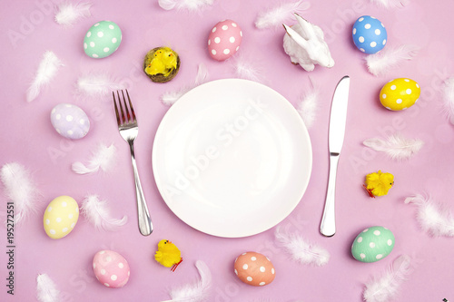 Easter table setting with cutlery and colorful eggs on violet table. Copy spase.