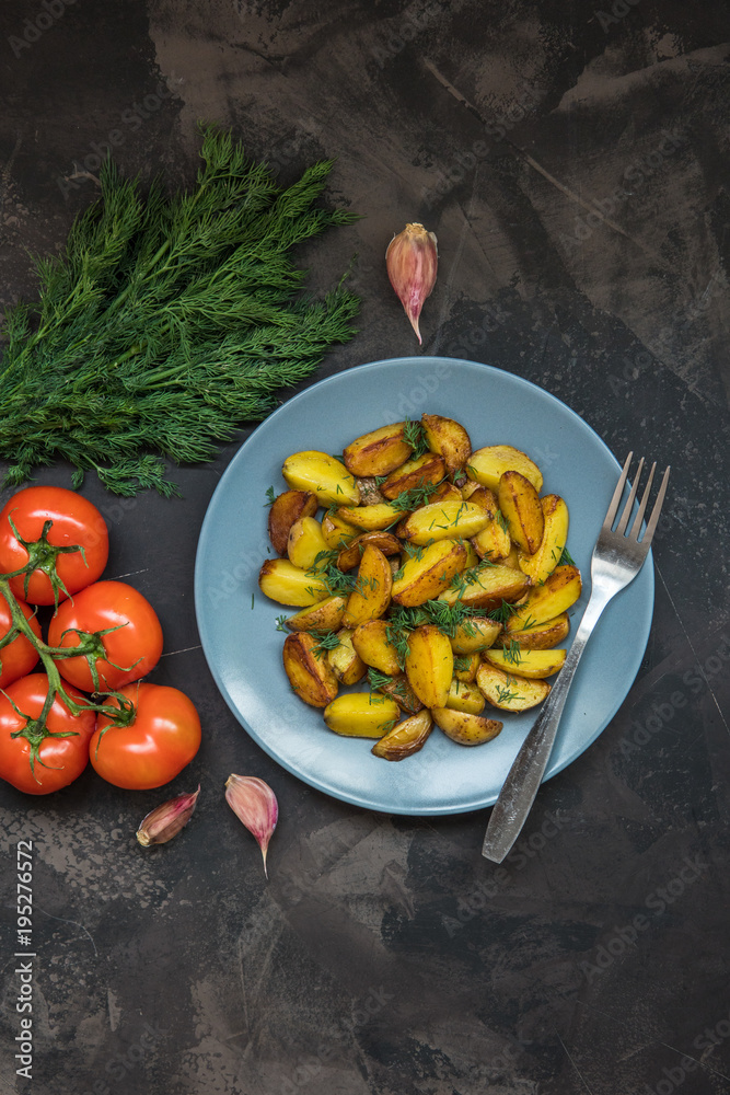 Fried baby potatoes, green, tomatoes and garlic on a dark background