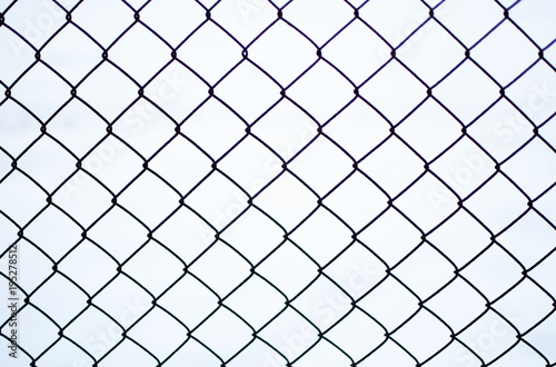 Rusty chain link fence of steel netting on white snow background in cold winter day.
