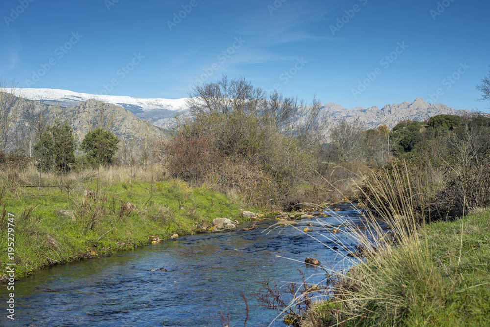 Views of the Fuentiduena stream on its way through the city of Cerceda, in the province of Madrid, Spain. In the background it can be seen The Guadarrama Mountains