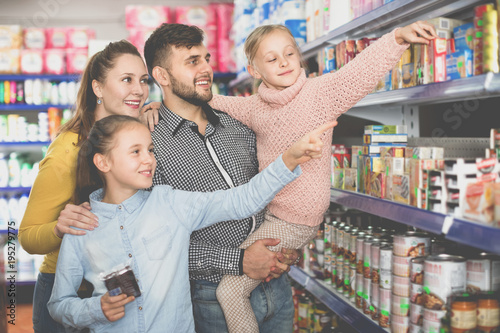 Happy family with two little girls buying food products in super