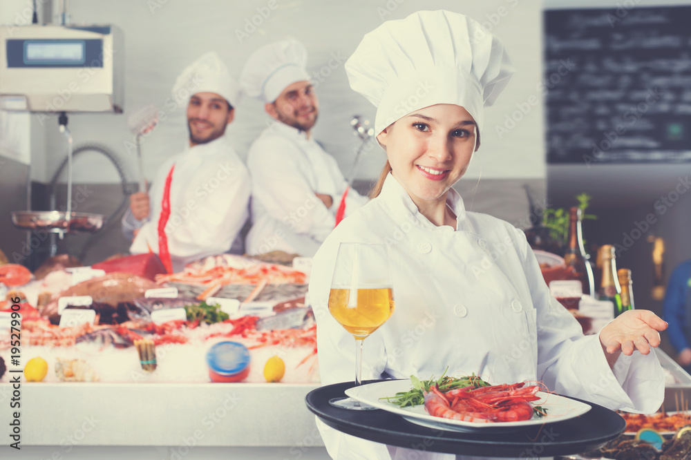 Attractive female chef with serving tray, offering dishes in fish restaurant