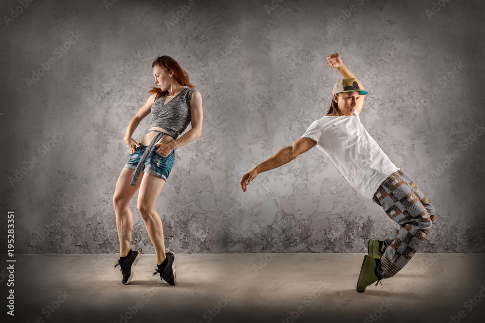 Hip Hop dancer in dynamic action jump on the grunge grey backgro