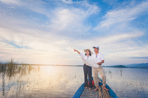 Travel man and woman with mapk standing on tail of the boat with lake and mountain view, Travel concept photo