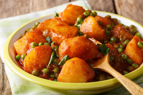 Indian hot Aloo Matar - potatoes, green peas, herbs and spicy sauce closeup on a plate. horizontal