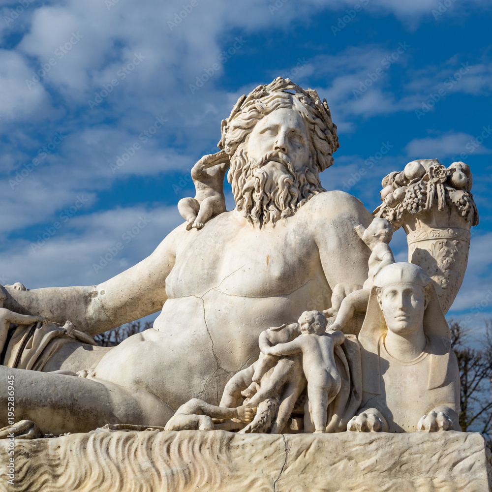 A statue of the Colossus Nile in the Jardin des Tuileries in Paris against a bright blue sky with white clouds A statue of the Colossus Nile in the Jardin des Tuileries in Paris against a bright blue sky with white clouds