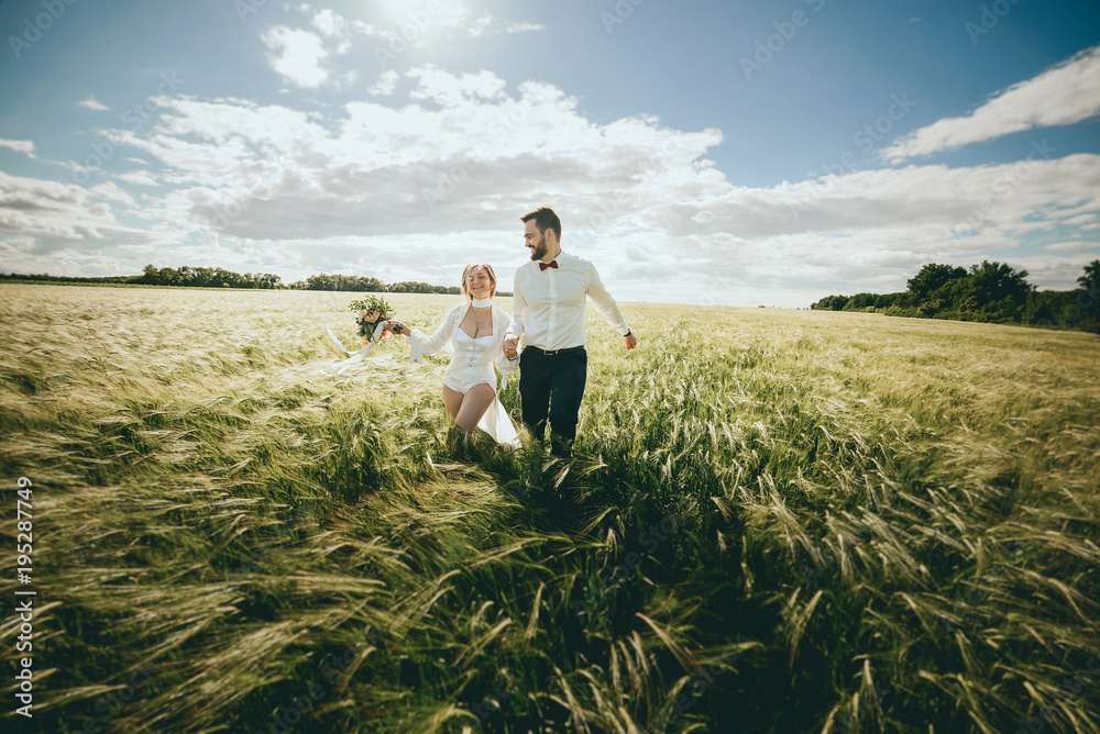 Married couple running in a field, having fun and smiling. She is looking back. Married couple running in a field, having fun and smiling. She is looking back.