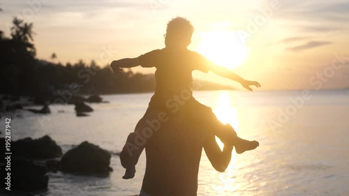 Cheerful father and son in eyeglasses spend happy time playing on tropical beach at beautiful sunset. slow motion. 3840x2160