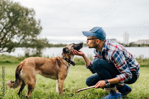 Fotografia Adult stylish man playing with loving pet
