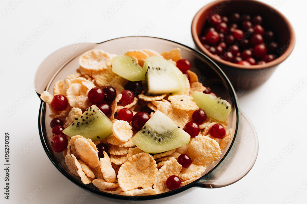 delicious crispy cornflakes with kiwi pieces and cranberries in bowl on white background, closeup, healthy breakfast delicious crispy cornflakes with kiwi pieces and cranberries in bowl on white background, closeup, healthy breakfast