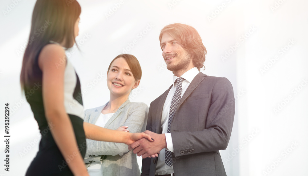 Businesspeople shaking hands against room with large window loo Businesspeople shaking hands against room with large window loo