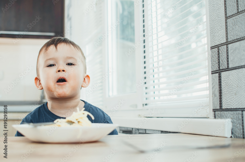 The child in the kitchen at the table eating macaroni and interesting view from the top