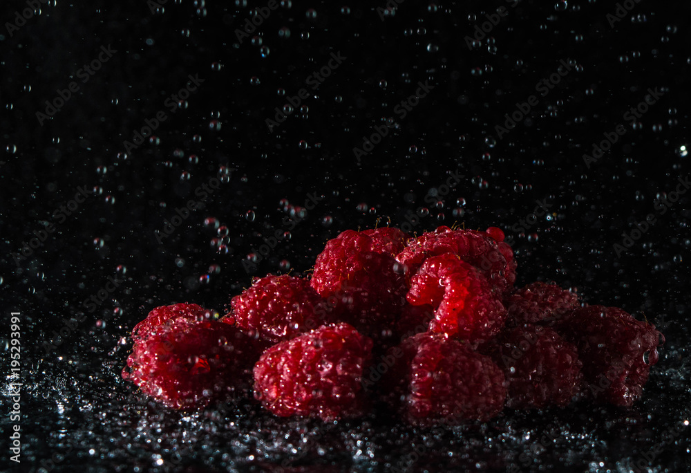Fresh raspberries in the rain in front of a black background Fresh raspberries in the rain in front of a black background