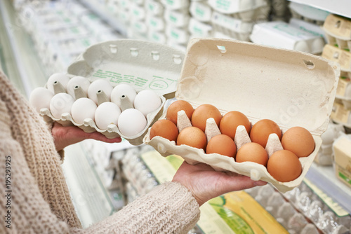 Woman with packs of white and brown eggs in store
