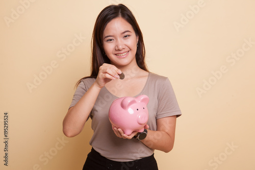 Asian woman with coin and pig coin bank.