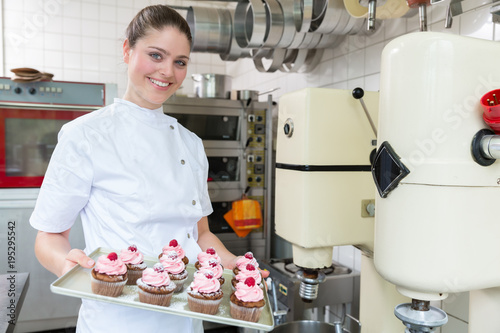 Proud confectioner or Patissier showing muffins she baked