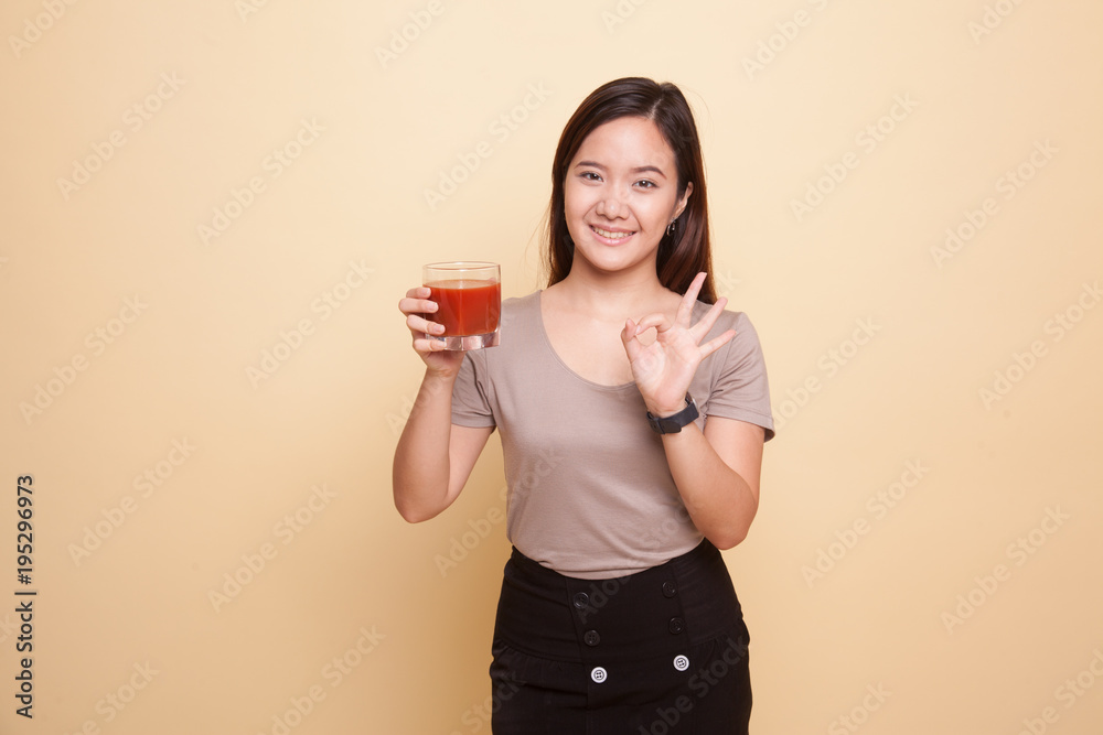 Young Asian woman show OK with tomato juice. Young Asian woman show OK with tomato juice.