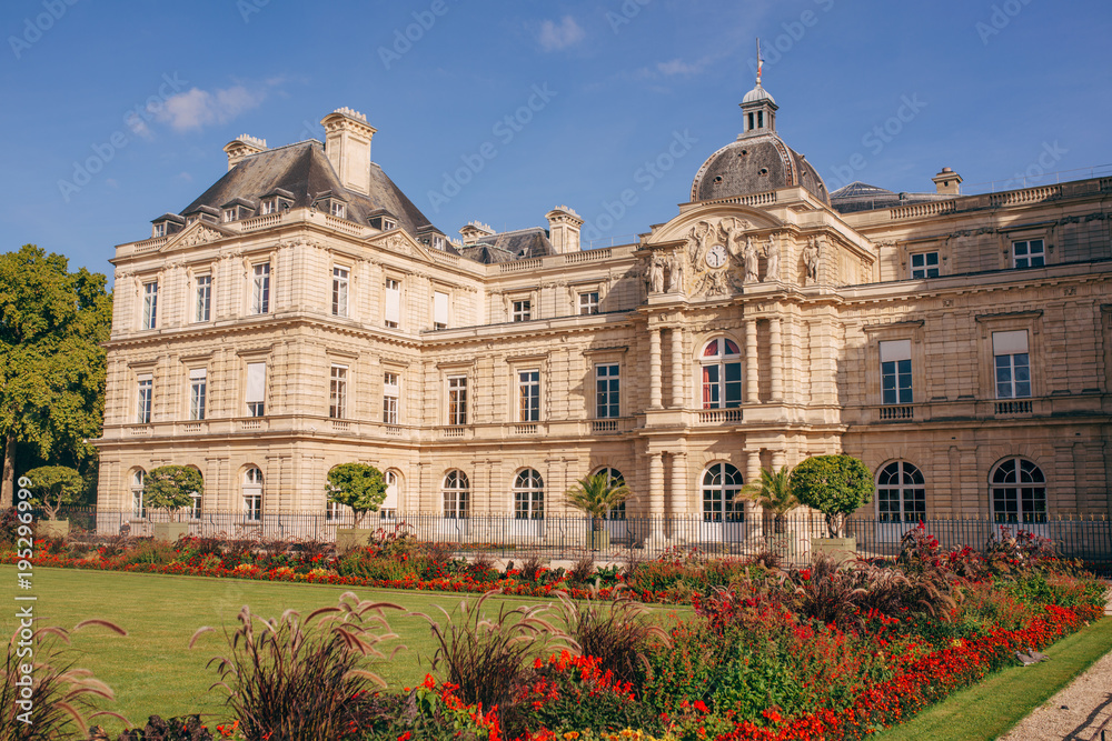 Luxembourg Gardens with yellow flowers, green grass, sculptures, chairs.