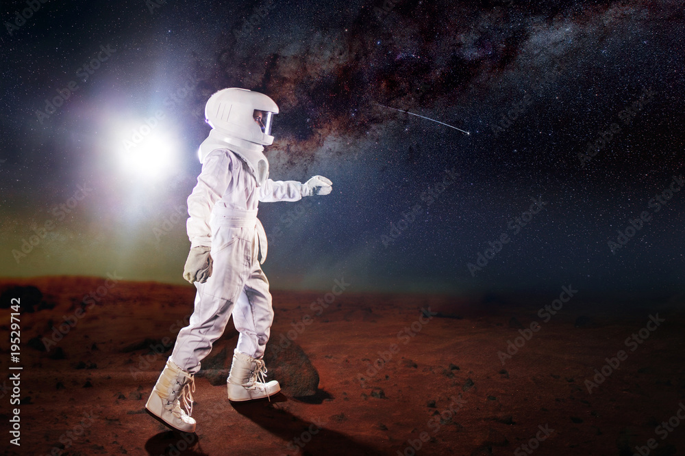 Portrait of astronaut in a space suit. Futuristic astronaut on the planet, standing and stretches hand away