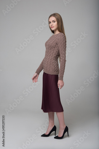 Young beautiful long-haired girl in knitted blouse and brown skirt