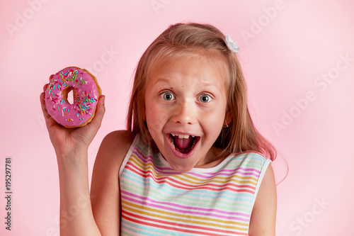 young beautiful happy and excited blond girl 8 or 9 years old holding donut on her hand looking spastic and cheerful in sugar addict concept photo
