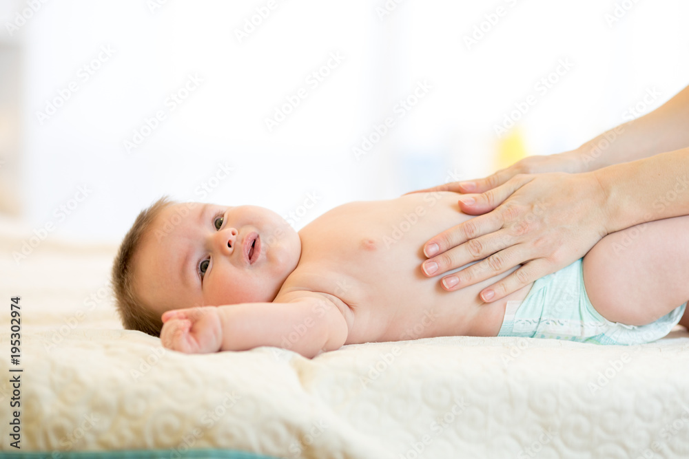 Mother massaging crying baby with colic Mother massaging crying baby with colic