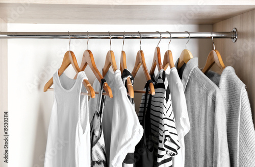 Hangers with different clothes in wardrobe closet