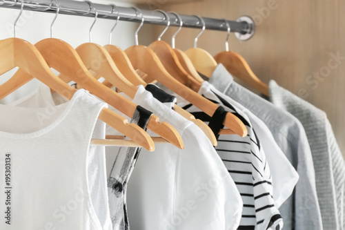 Hangers with different clothes in wardrobe closet photo