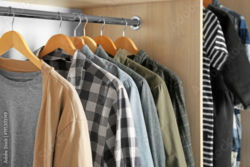 Hangers with different clothes in wardrobe closet