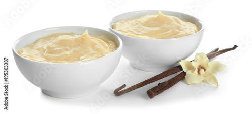 Fotografia Tasty vanilla pudding in dishes and sticks with flower on white background