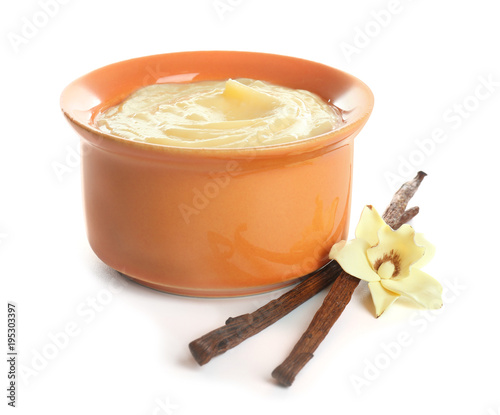 Foto Tasty vanilla pudding in ramekin and sticks with flower on white background