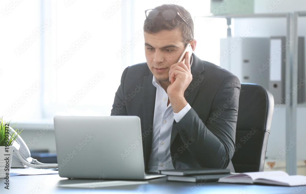 Young man in office wear talking on phone at workplace Young man in office wear talking on phone at workplace