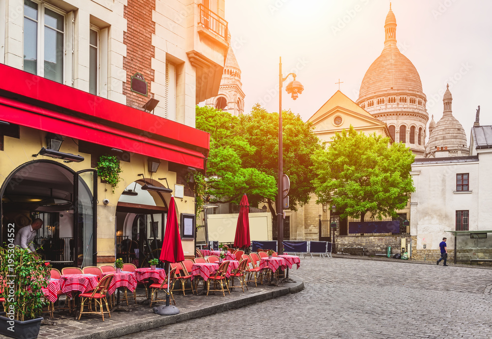 Obraz premium Przytulna ulica z stolikami kawiarni w dzielnicy Montmartre w Paryżu, Francja