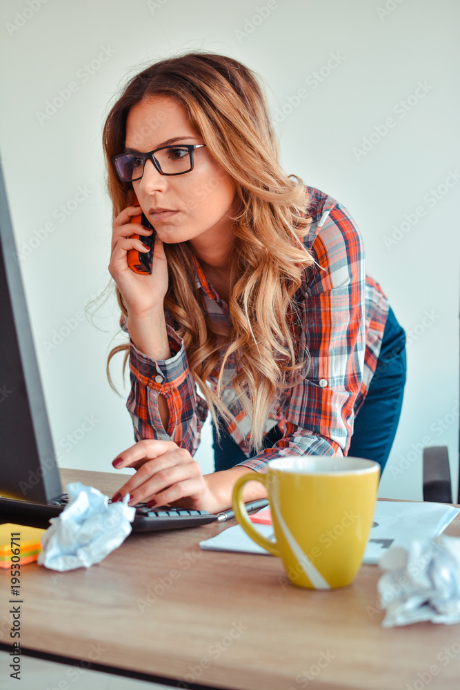 Creative woman talking on phone while sitting at desk in office Creative woman talking on phone while sitting at desk in office