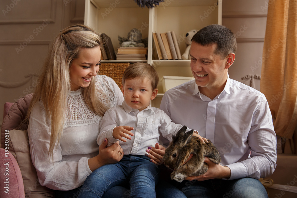 Happy family playing with Easter bunny and celebrating Easter day. Portrait of mother, father and son at Easter sunday. Domestic life of young family Happy family playing with Easter bunny and celebrating Easter day. Portrait of mother, father and son at Easter sunday. Domestic life of young family