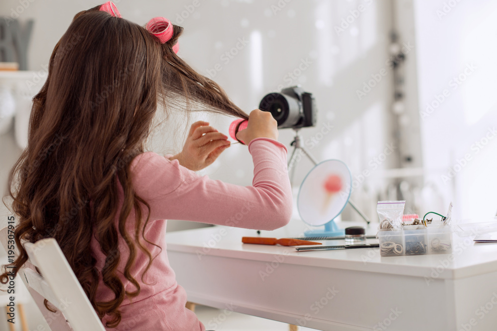 Lovely hairstyle. Charming pre-teen girl recording a video tutorial and  showing how to use hair rollers correctly, curling her hair locks with them  Stock Photo | Adobe Stock
