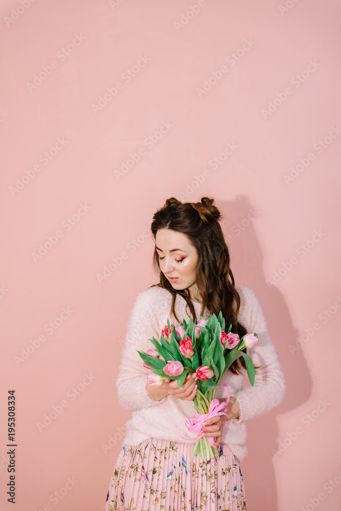 A girl in a pink room with a bouquet of tulips in her hands
