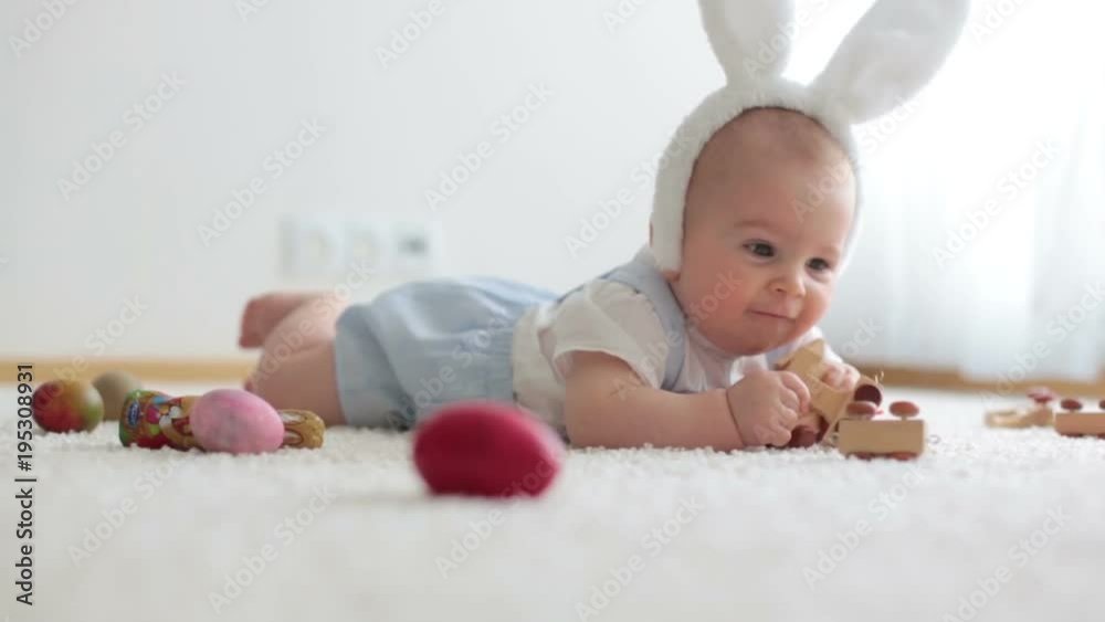 Cute little toddler child, baby boy, in sunny living room playing with Easter chocolate bunny and colorful Easter eggs Cute little toddler child, baby boy, in sunny living room playing with Easter chocolate bunny and colorful Easter eggs