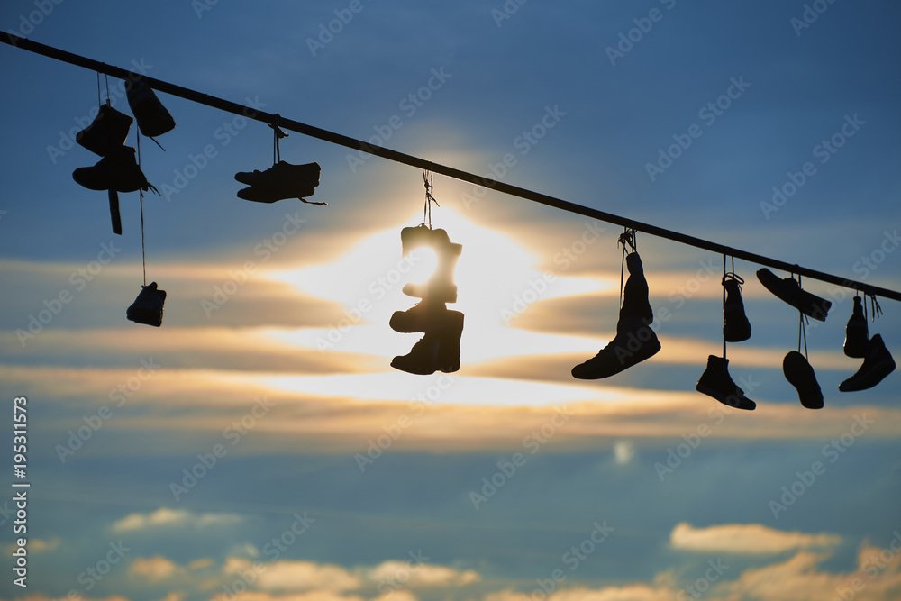 Old Shoes hanging on electrical wire against a sky. Shoe tossing
Old Shoes hanging on electrical wire against a sky. Shoe tossing